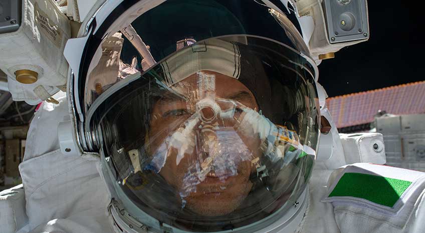 An astronaut takes a selfie while in his helmet and suit